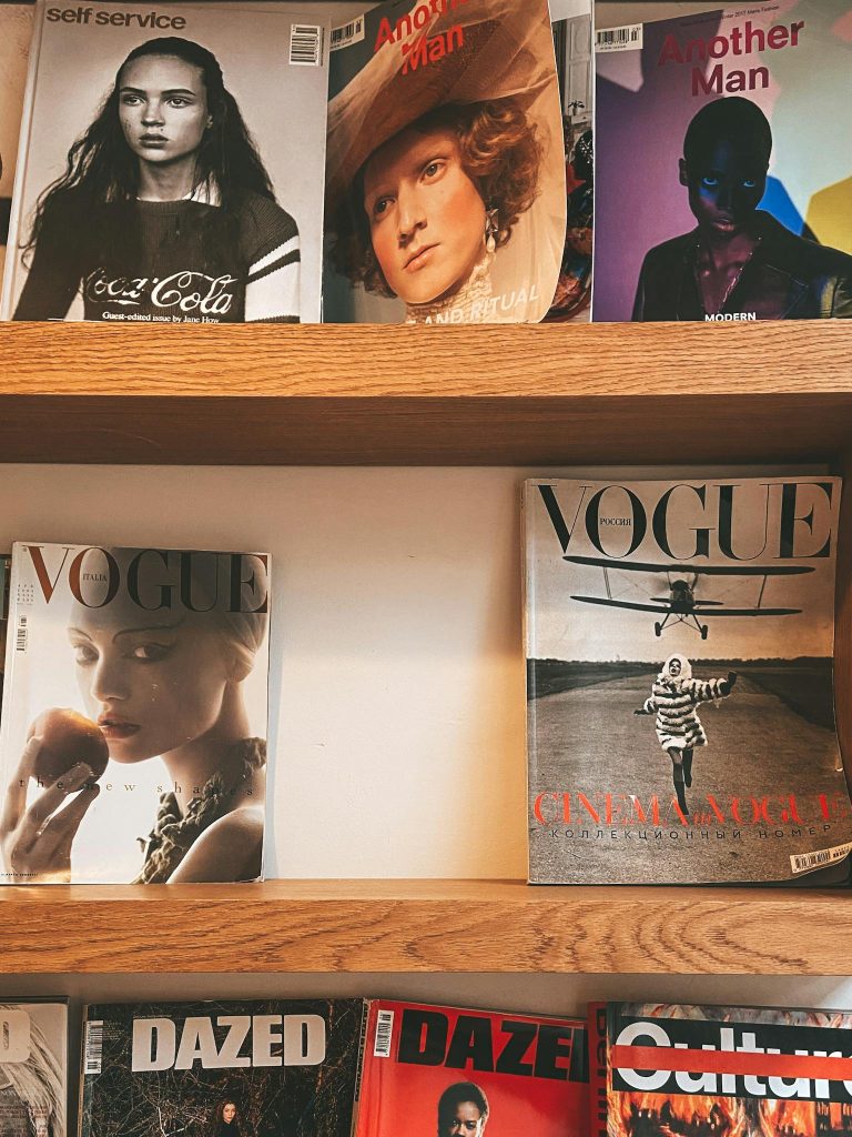 A collection of fashion magazines neatly arranged on a wooden shelf.