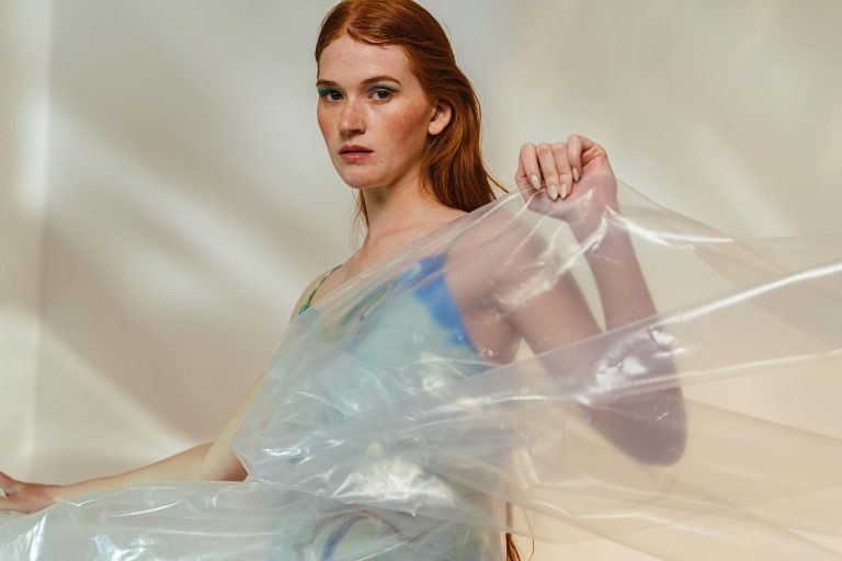 Artistic studio portrait of a woman with red hair posing with plastic sheets.